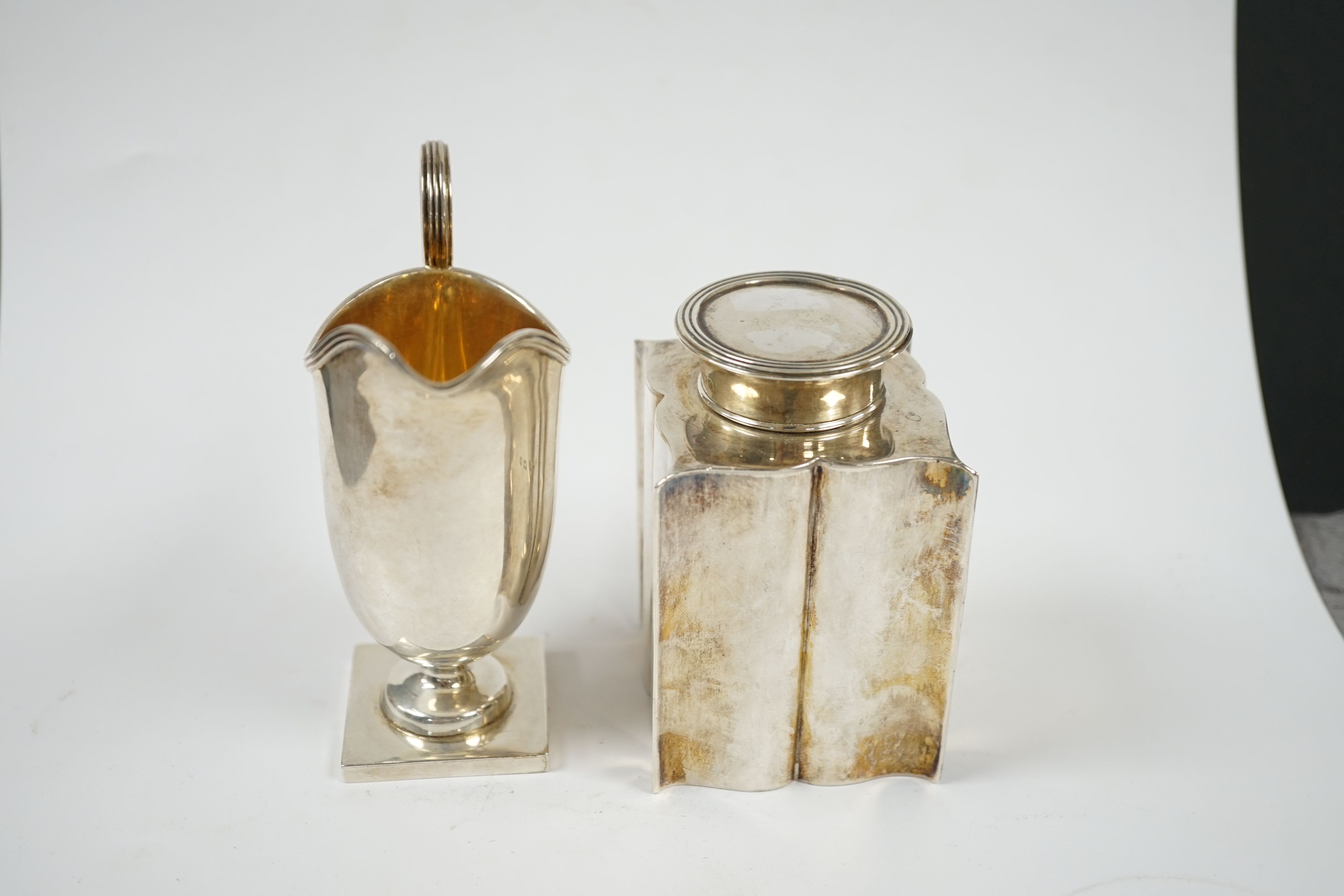 An Edwardian silver ‘bats wing’ tea caddy, Birmingham, 1906, 95mm and a George V silver cream jug. Condition - fair